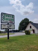 una señal para una mezcla de ciudad y campo frente a un edificio en Town and Country INN, en Rogers