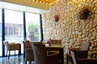 a restaurant with a stone wall and tables and chairs at Haiye Guest House in Kenting