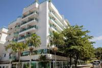 Un edificio alto y blanco con palmeras delante. en Angra Beach Hotel, en Angra dos Reis