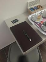un bolígrafo sentado encima de un cuaderno en un escritorio en Hotel Calaluna, en Biella