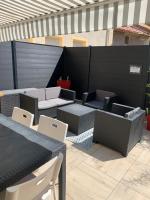 a patio with tables and chairs and a black fence at Appartement la corde a linge Gruissan village avec terrasses in Gruissan