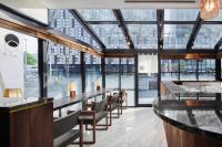 a restaurant with a long bar with chairs and windows at EN HOTEL Hakata in Fukuoka