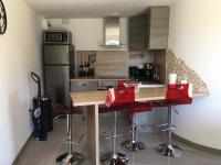 a kitchen with a wooden counter and red bar stools at Kervran in Plouhinec