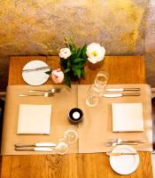 Una mesa de madera con platos y servilletas blancas y flores. en Der espenhof Landhotel, Tagungshotel & Weingut, en Flonheim
