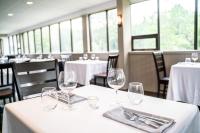 een restaurant met witte tafels en stoelen met wijnglazen bij Nomi Resort in Harcourt