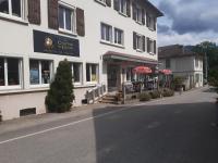 Un gran edificio blanco con mesas y sombrillas en una calle. en Chalet dans village, en Saint-Maurice-en-Trièves