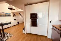 a kitchen with white cabinets and a refrigerator and a staircase at **La Bretonnerie, bel appartement de standing in Concarneau