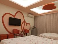 a hotel room with two beds and a flat screen tv at Happy Heart B&amp;B in Taitung City