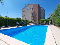 a swimming pool with chairs and a building in the background at Apartment Marko by Interhome in Bibinje