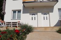 a white house with white doors and flowers at Nikolića kuća in Mitrovac