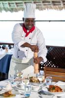 a chef is preparing food on a table at Hotel Club Dongwe in Pingwe