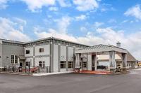 a large white building with a parking lot at Days Inn &amp; Suites by Wyndham Bowling Green in Bowling Green