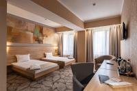 a hotel room with two beds and a desk at Renion Park Hotel in Almaty