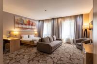 a hotel room with a bed and a couch and chairs at Renion Park Hotel in Almaty
