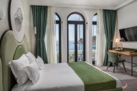 Una habitación de hotel con una cama, un escritorio y ventanas. en Heritage Hotel Porin Makarska, en Makarska