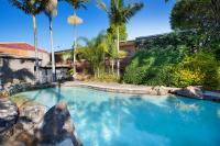 Una piscina con palmeras en un patio. en Villa Noosa Hotel, en Noosaville