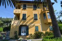 un edificio amarillo con persianas verdes y una palmera en Villa Margherita, en Levanto