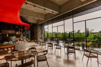 ロナバラにあるRadisson Resort and Spa Lonavalaのテーブルと椅子と大きな窓のあるレストラン