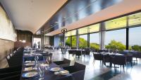 a restaurant with black tables and chairs and large windows at L'Hotel de Hiei in Kyoto