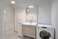 a white bathroom with a washing machine and a sink at Charmant appartement sur le remblai de Pleneuf Val Andre in Pléneuf-Val-André