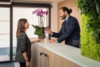 a man and a woman standing at a counter with flowers at Résidence de Diane - Toulouse in Toulouse