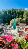 Un patio con una sombrilla verde y mesas y sillas. en Pensiunea Kalinder, en Buşteni