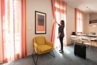 a woman opening curtains in a room with a yellow chair at Résidence de Diane - Toulouse in Toulouse