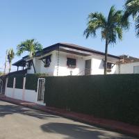una casa blanca con palmeras y una valla en Lovely location , right downtown Puerto Plata, en San Felipe de Puerto Plata
