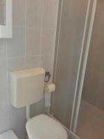 a small bathroom with a toilet and a shower at Sea view room in Bol