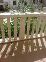 a white fence with its shadows on the ground at Sea view room in Bol
