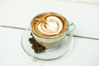 a cup of coffee on a plate with coffee beans at Stay Banaras - A Boutique Hotel in Varanasi