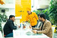 three men sitting around a table with a man in a chef uniform at Stay Banaras - A Boutique Hotel in Varanasi