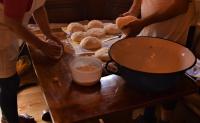 Dos personas haciendo bagels en una mesa de madera con una olla. en Šurička bajka, en Loznica
