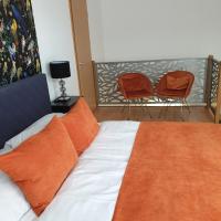 a bedroom with a bed with orange pillows and two chairs at Grand Paradise Apartman in Miskolc