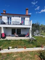 a white house with red chairs and a patio at Olivia Valkanela App 1 in Vrsar