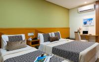 a hotel room with two beds and a desk at Hotel Santorini in Vila Velha