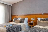 a hotel room with two beds and a window at Hotel Santorini in Vila Velha