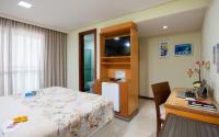 a bedroom with a bed and a desk and a television at Hotel Santorini in Vila Velha