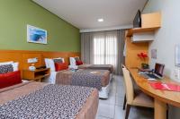 a hotel room with three beds and a desk at Hotel Santorini in Vila Velha