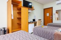 a small room with two beds and a desk at Hotel Santorini in Vila Velha