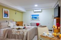 a bedroom with a bed and a table and a couch at Hotel Santorini in Vila Velha