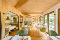 Un restaurante con mesas blancas y sillas verdes. en Landhotel Hochlackenhof, en Fuschl am See