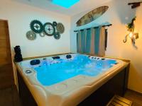 a jacuzzi tub in a room with a clock at Suite Cupidon- Domaine des trois châteaux in Moisenay