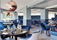 a dining room with tables and blue chairs at Formby Hall Golf Resort & Spa in Southport