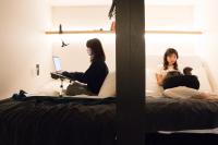 two women sitting on a bed with a laptop at The Millennials Kyoto in Kyoto