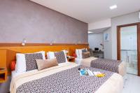 a hotel room with two beds with a book on it at Hotel Santorini in Vila Velha