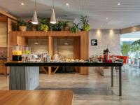 a bar in a restaurant with a person in the background at Novotel BH Savassi in Belo Horizonte