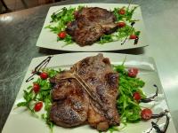 Dos platos de comida con carne y ensalada sobre una mesa. en Hotel Prunk, en Sežana