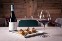 a bottle of wine and a plate of food and a glass at Alpen Chalet - Charme Mountain Hotel - in Schilpario