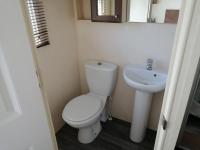 a small bathroom with a toilet and a sink at La Chanterie Agréable Mobil-Home Résidentiel Normand in Saint-Pair-sur-Mer